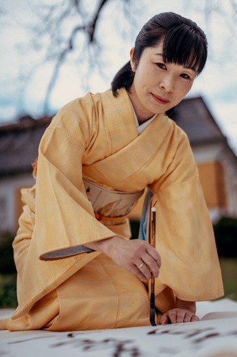 Autorka v žlutém kimono při psaní tuší